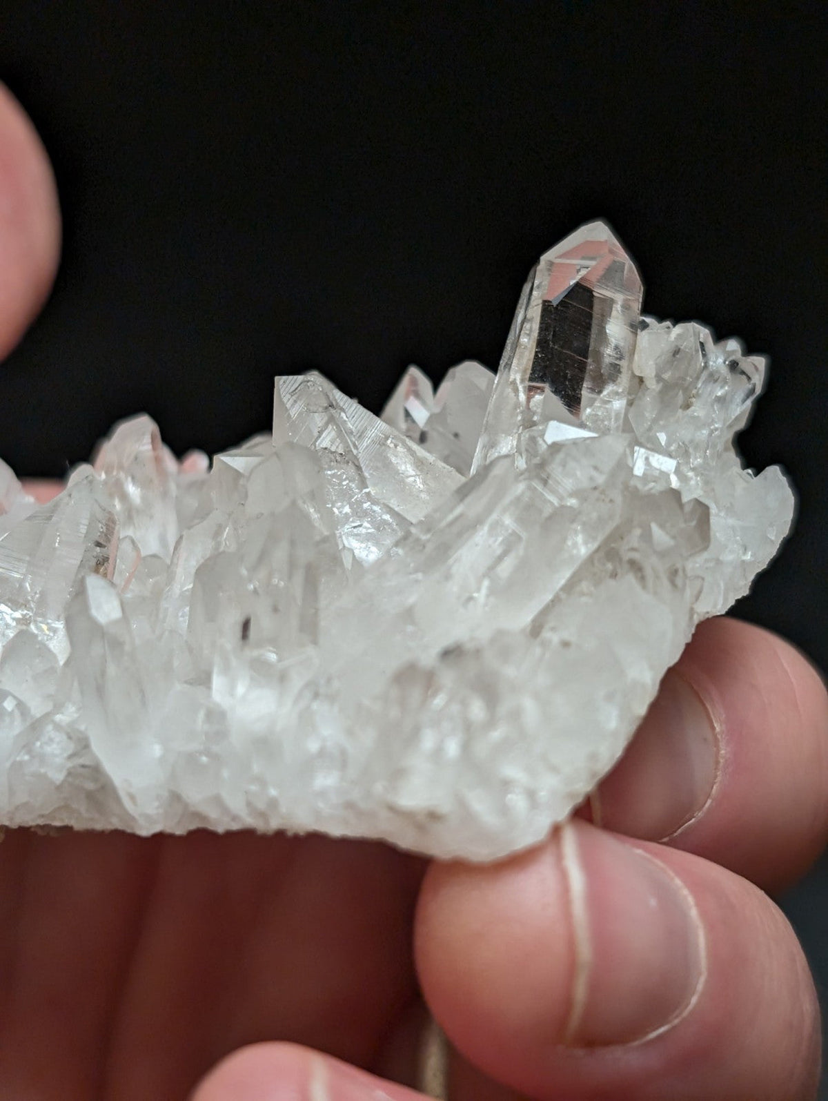 A clear, translucent quartz crystal cluster with sharp, faceted points and a natural, rugged texture.
