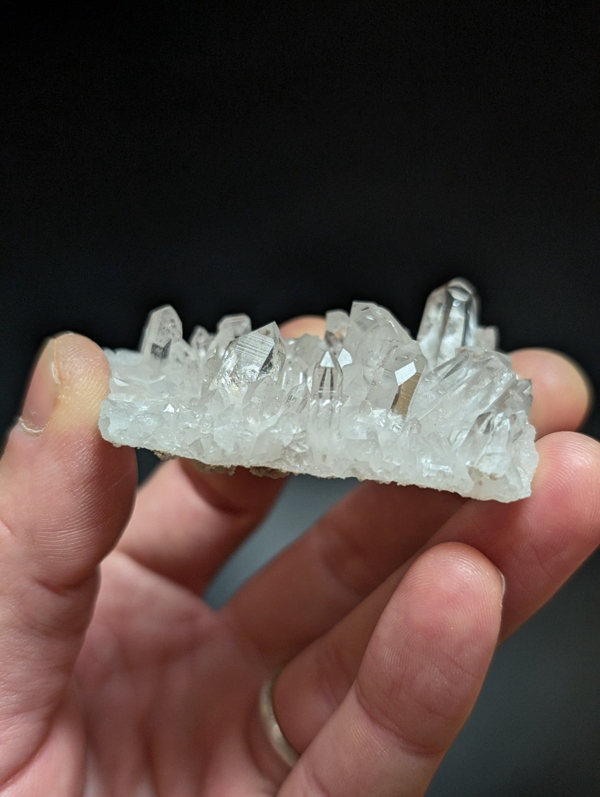 A translucent white quartz crystal cluster with sharp, faceted points and a rough-textured base.