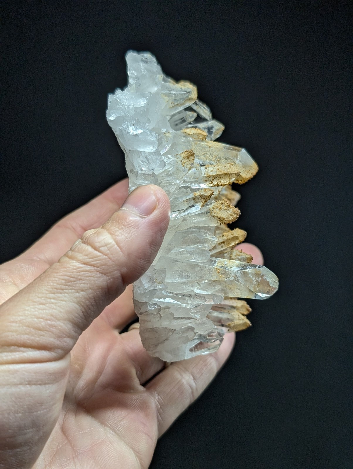 A translucent quartz crystal cluster with sharp, faceted points and golden-brown mineral inclusions.
