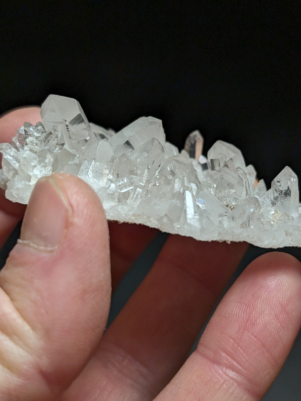 A translucent, clear quartz crystal cluster with sharp, faceted points and a natural, irregular formation.
