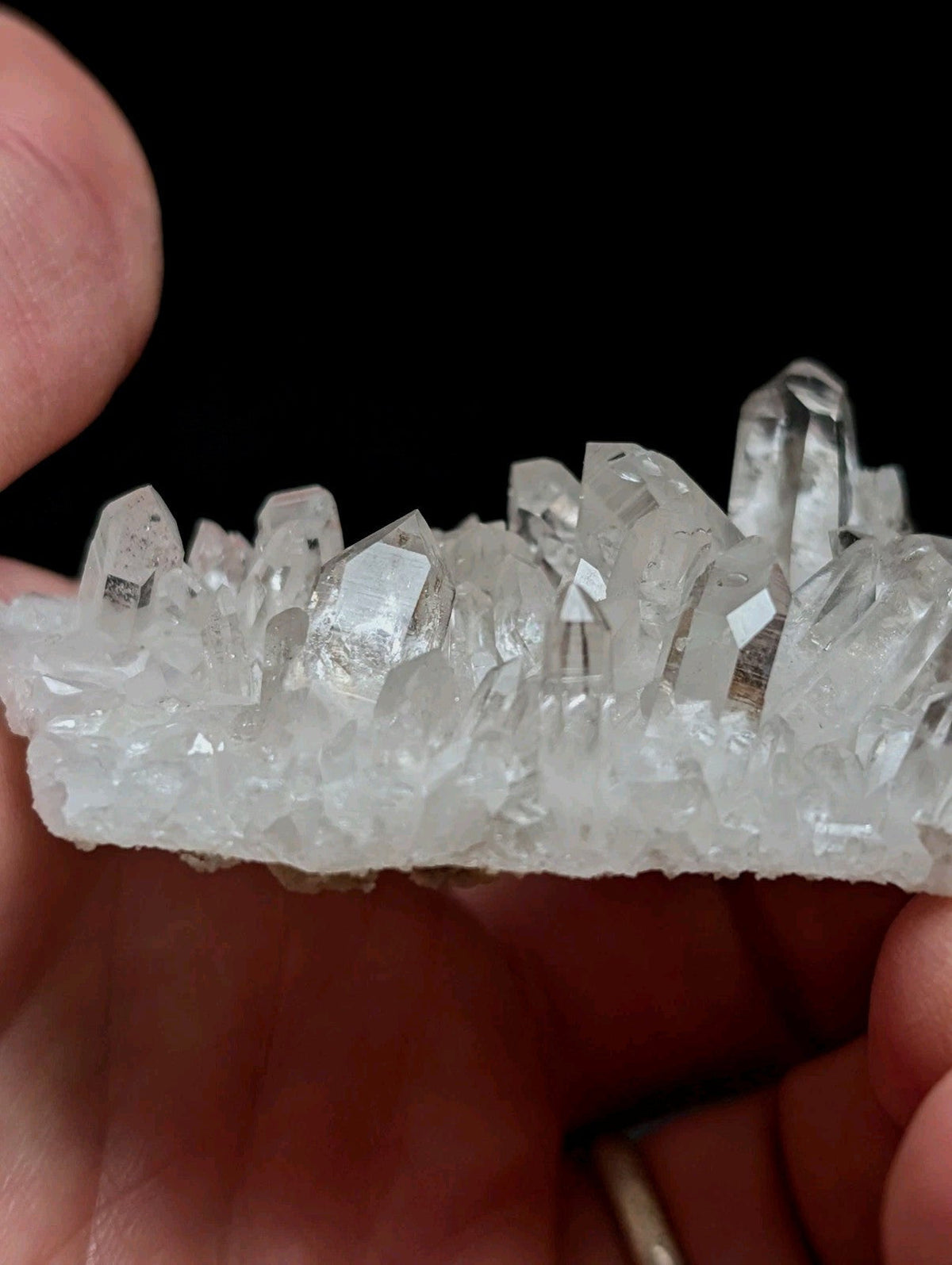 A clear quartz crystal cluster with sharp, faceted points and a translucent base.