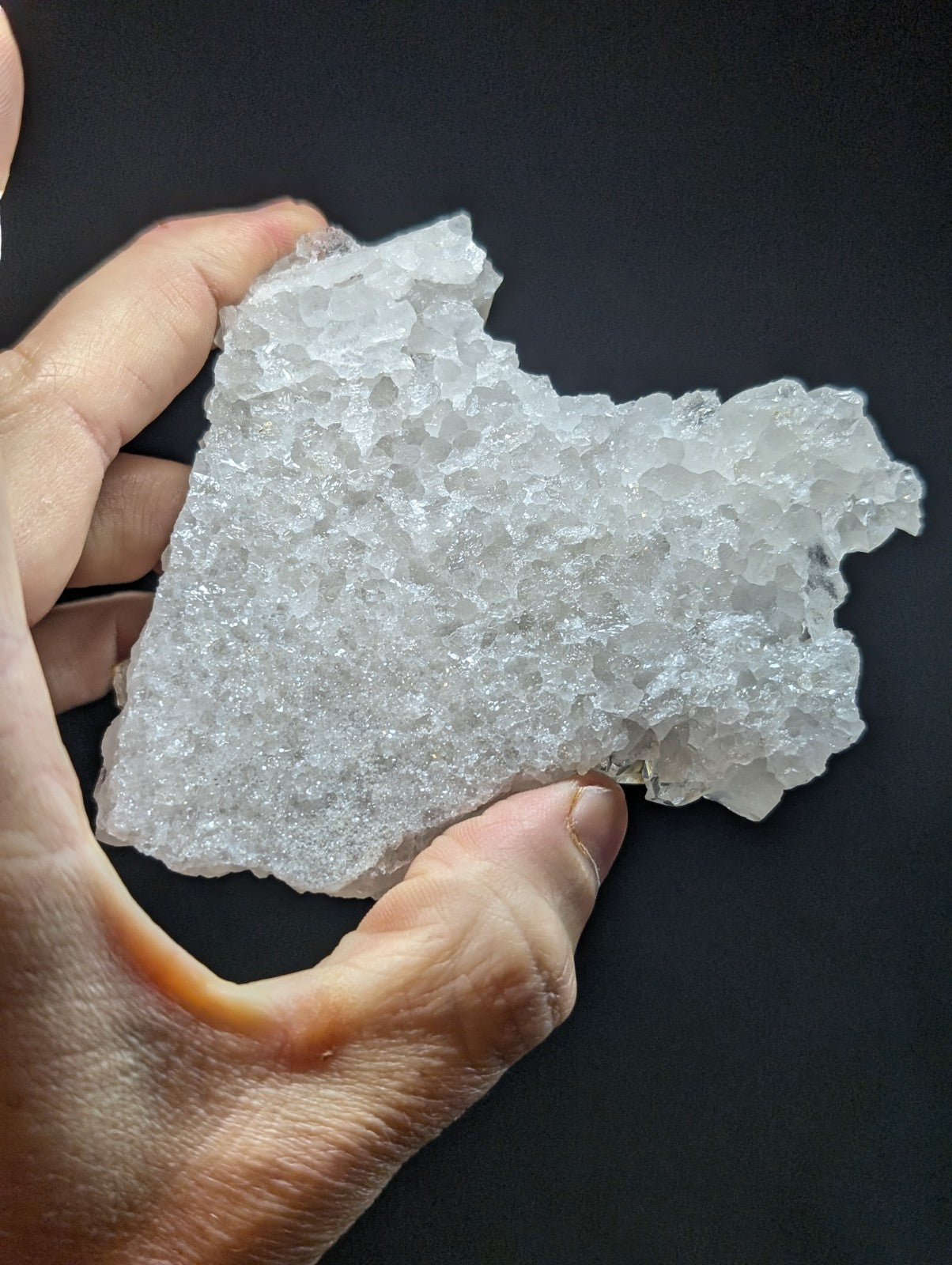A translucent, crystalline mineral specimen with a rough, jagged surface and irregular shape.