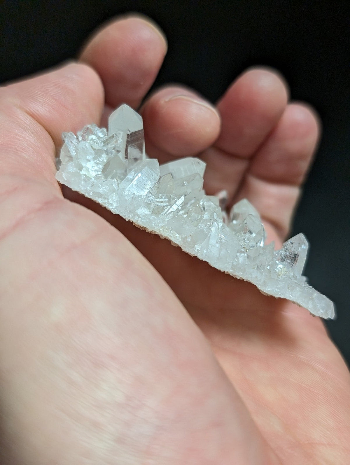 A translucent, clear quartz crystal cluster with sharp, faceted points and a natural, irregular base.