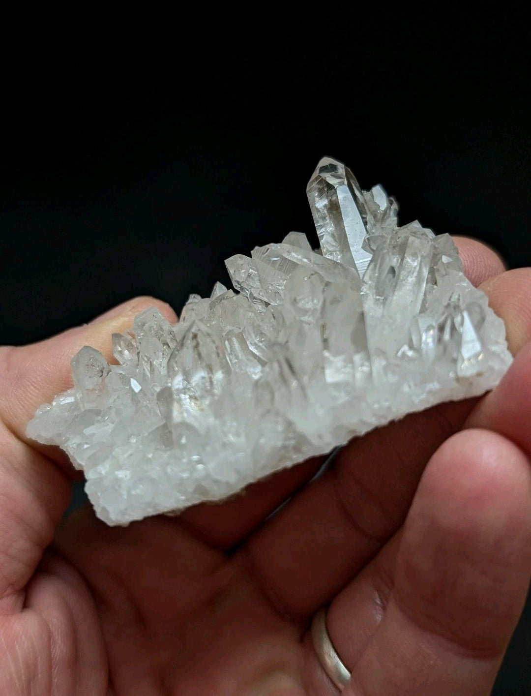 A clear quartz crystal cluster with sharp, faceted points and a translucent, glassy appearance.