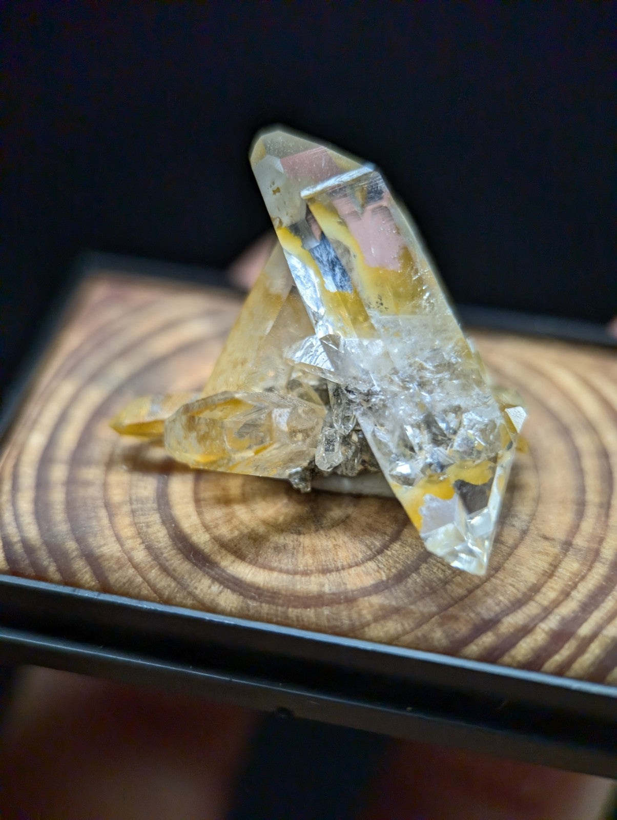 A translucent yellow and clear quartz crystal cluster with natural inclusions, displayed on a wooden surface.