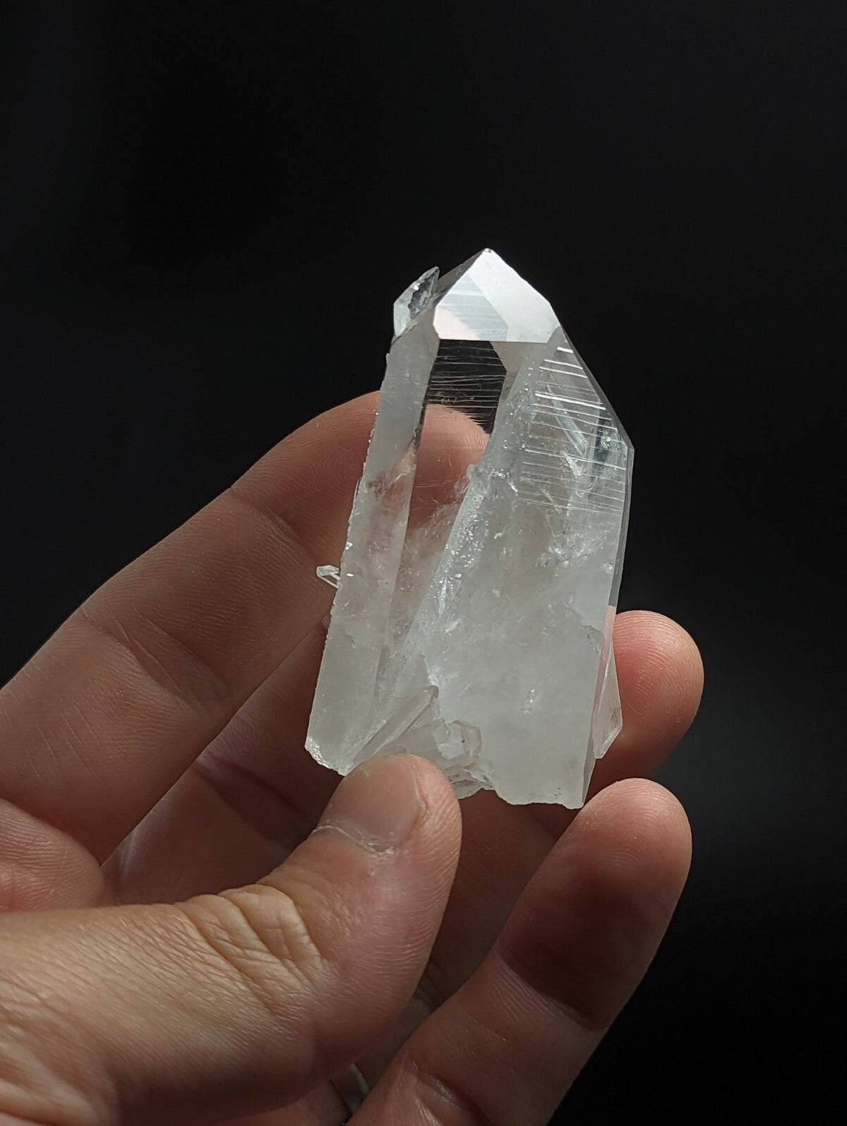 A translucent, clear quartz crystal with a pointed tip and visible internal striations.
