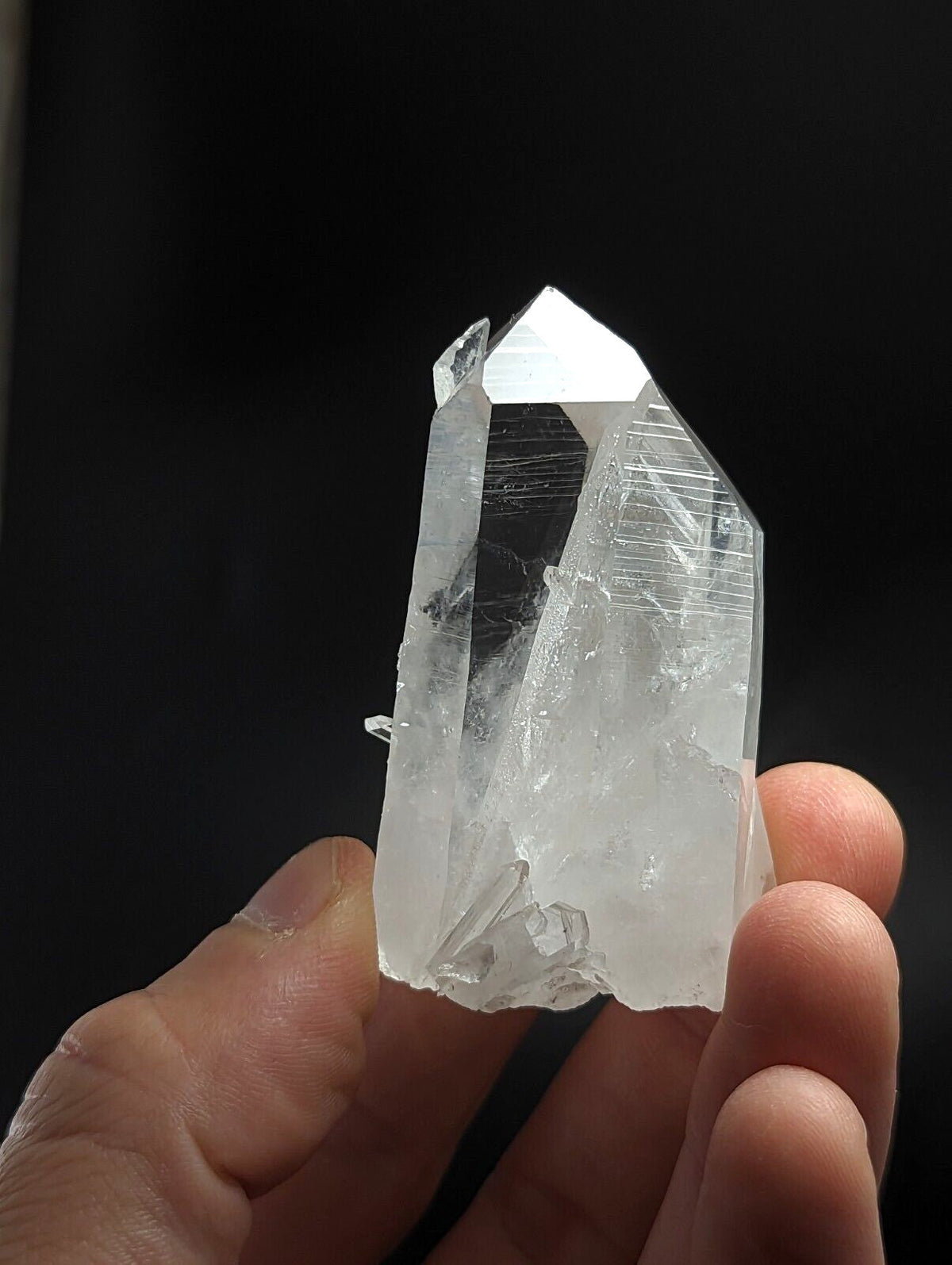 A translucent, clear quartz crystal with a pointed tip and visible internal striations.