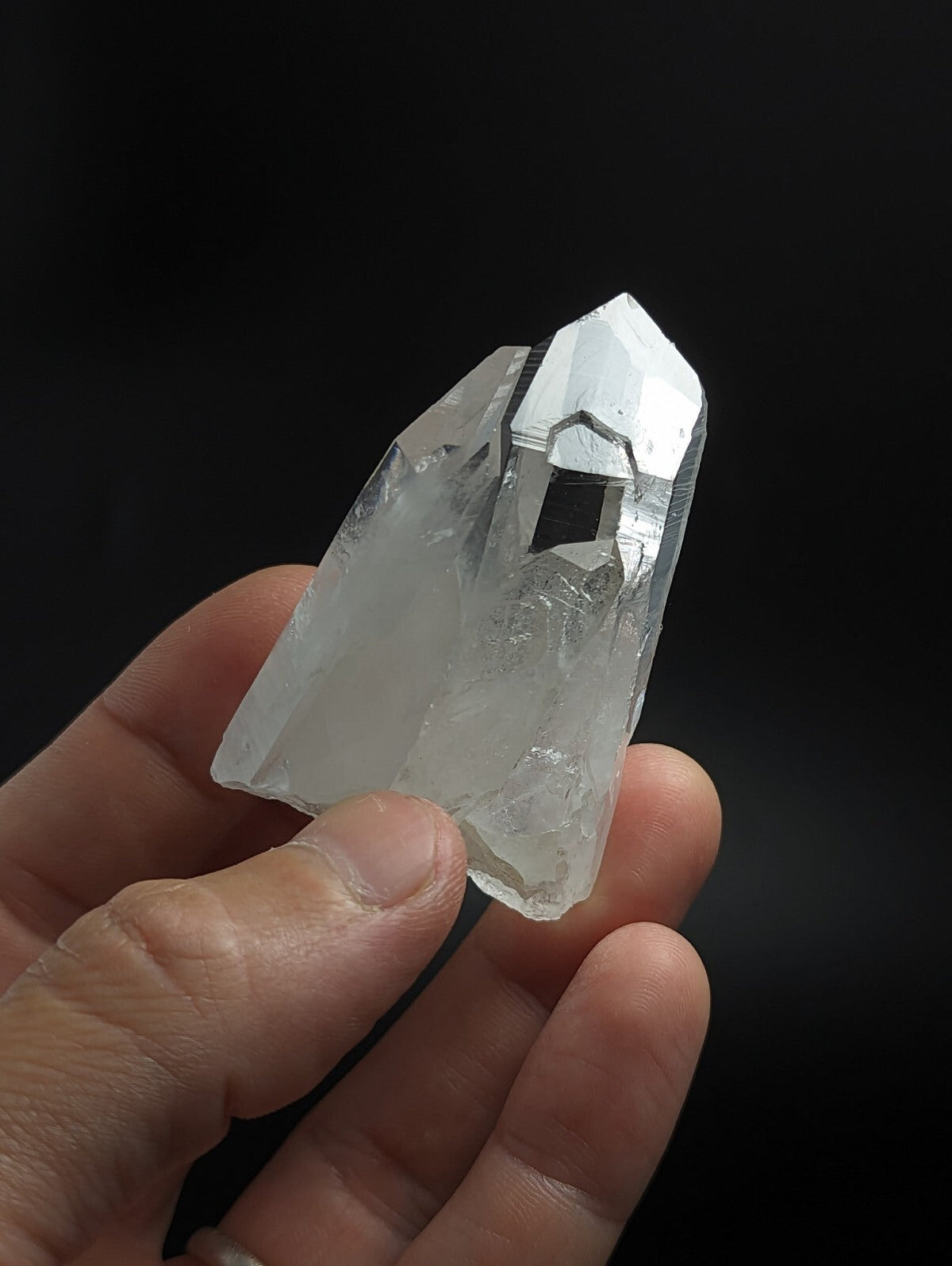 A clear, translucent quartz crystal with a pointed tip and natural facets.