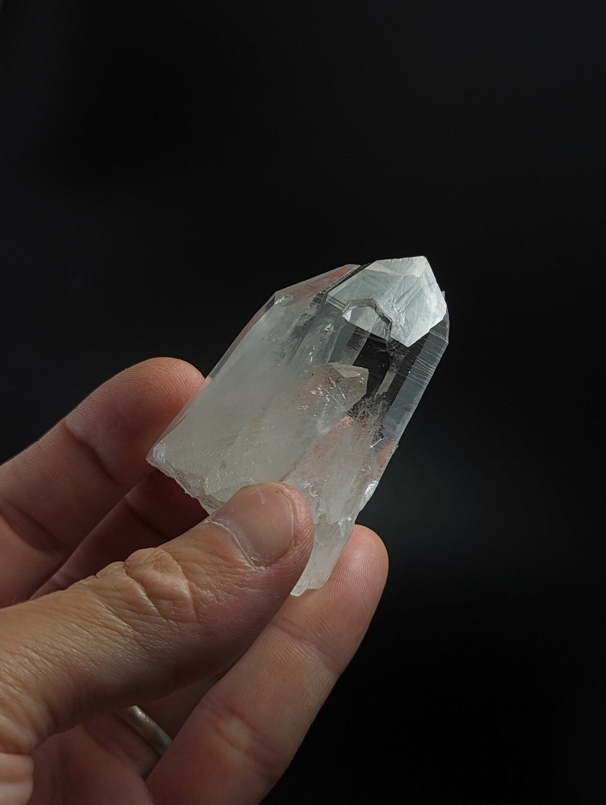 A clear, translucent quartz crystal with a pointed tip and natural facets.