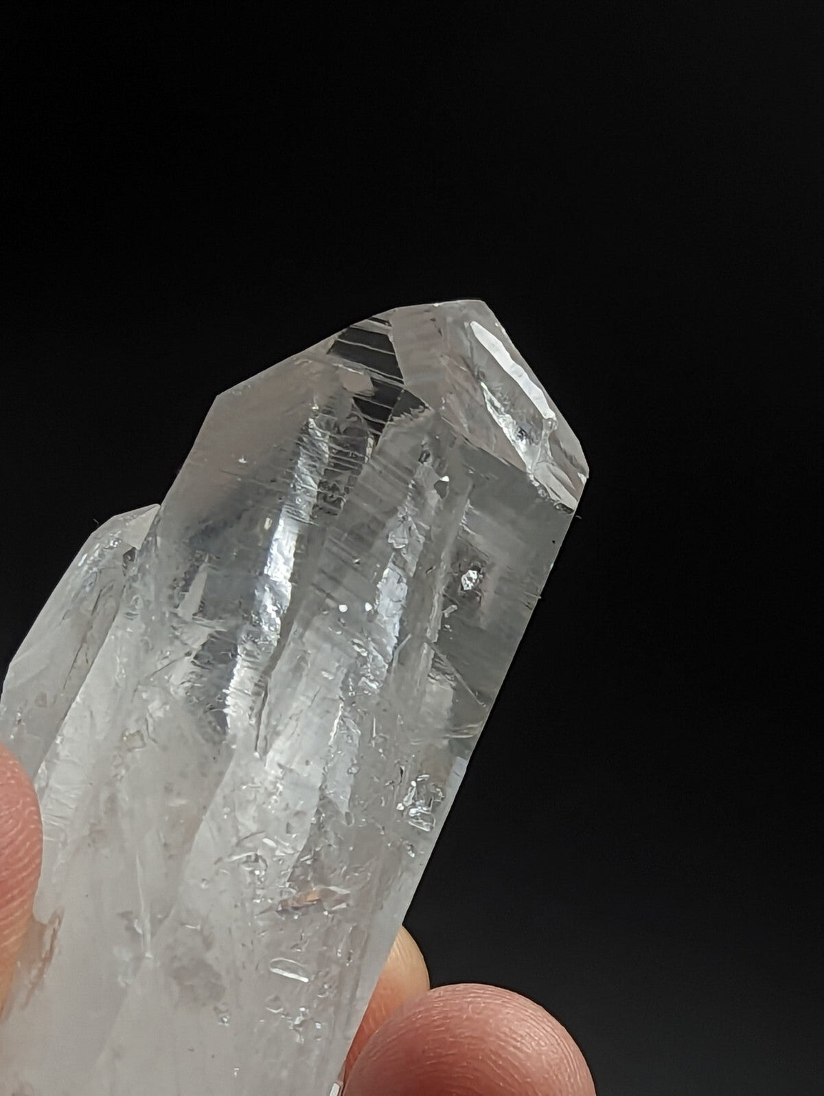 A clear, translucent quartz crystal cluster with sharp facets and natural internal striations.