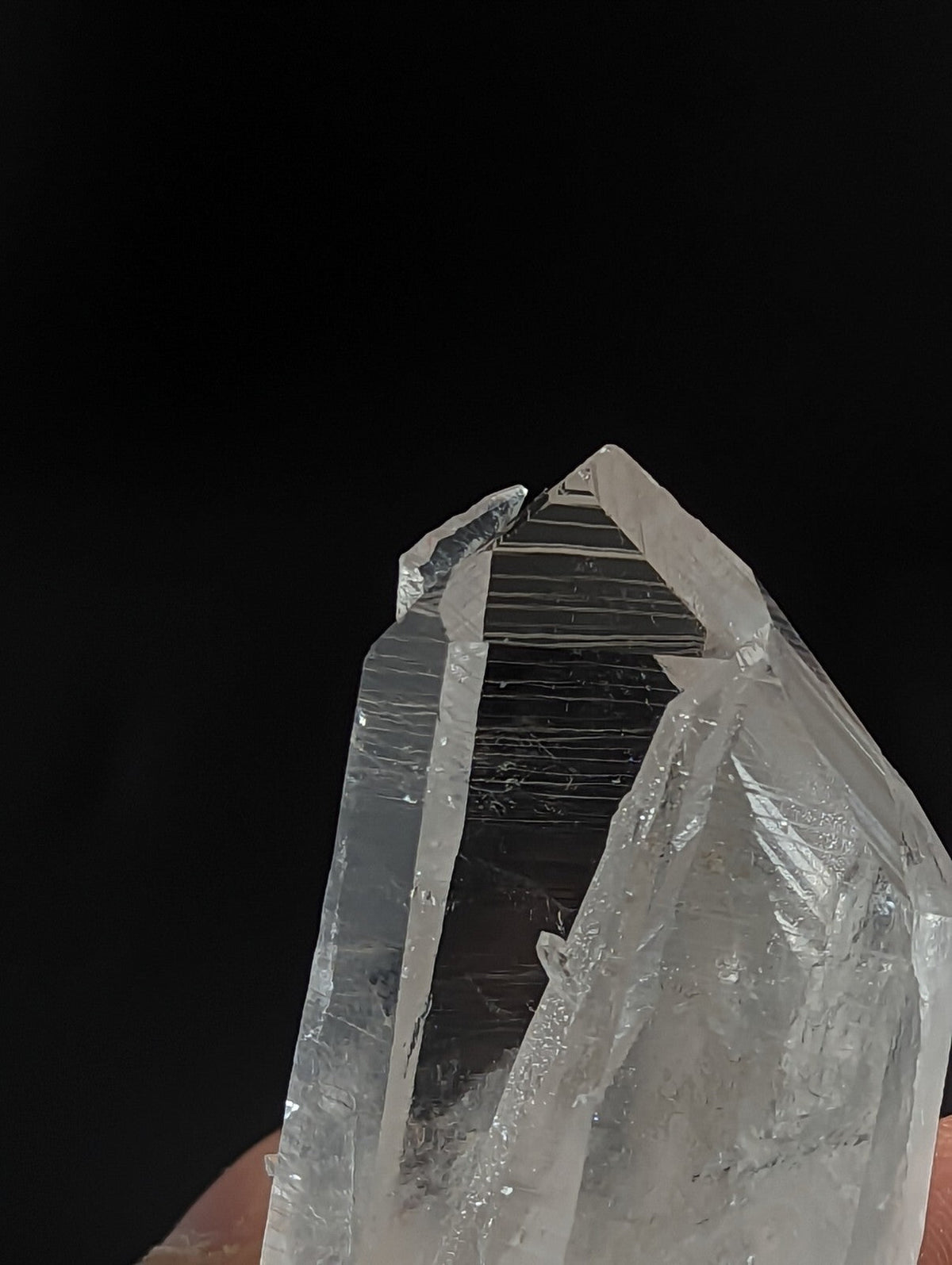 A translucent, clear quartz crystal with sharp, angular facets and subtle internal striations.