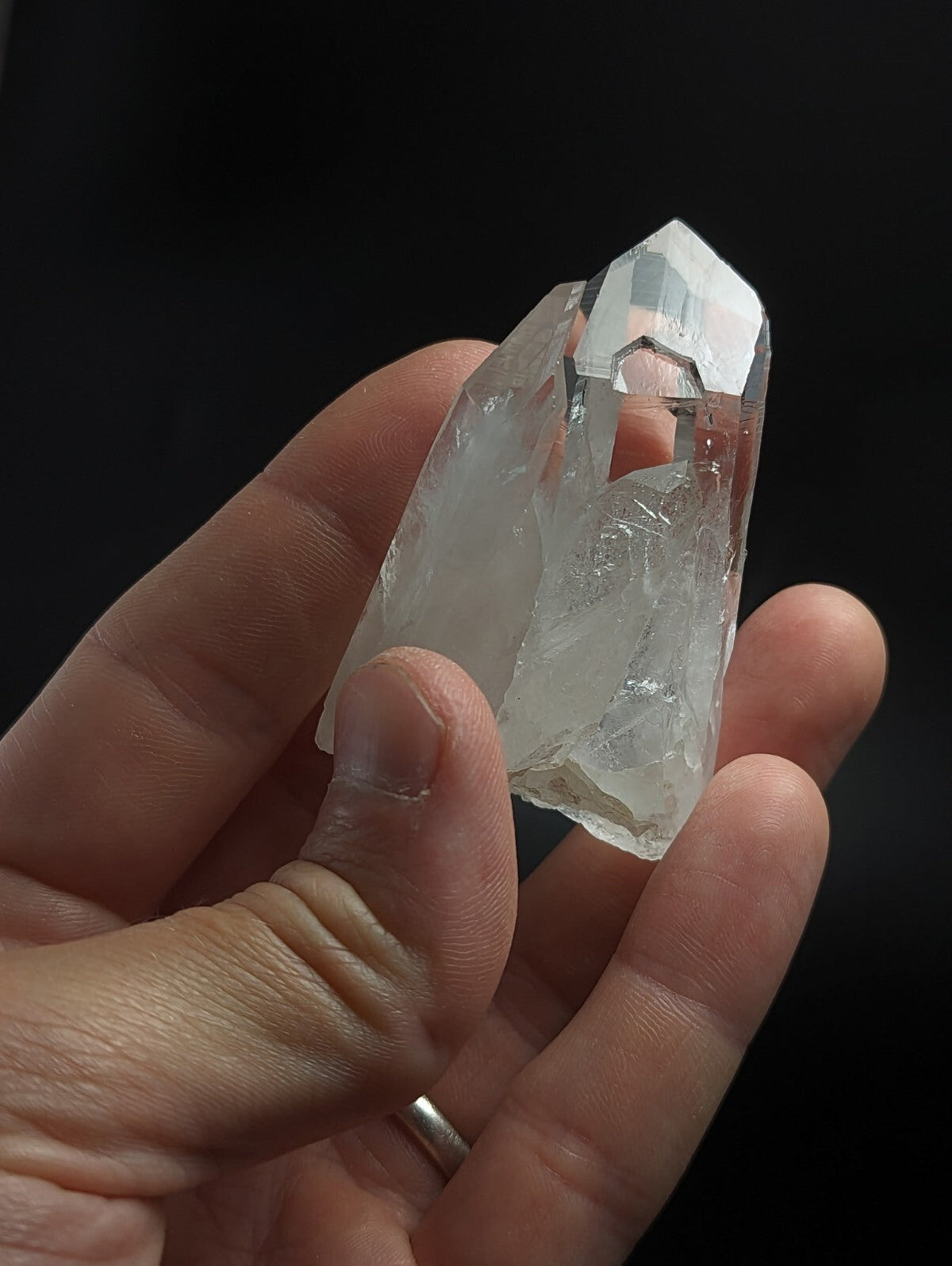 A translucent, clear quartz crystal with a pointed tip and natural facets.