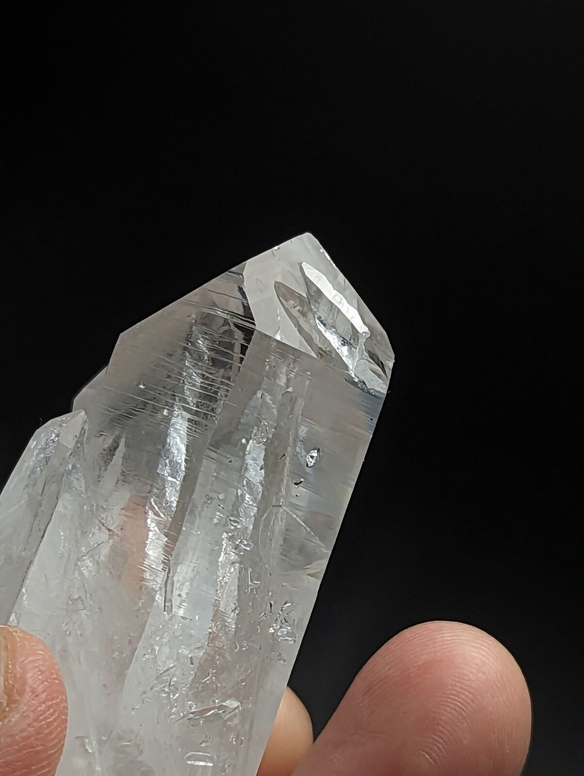A translucent, clear quartz crystal with a pointed tip and visible internal striations.