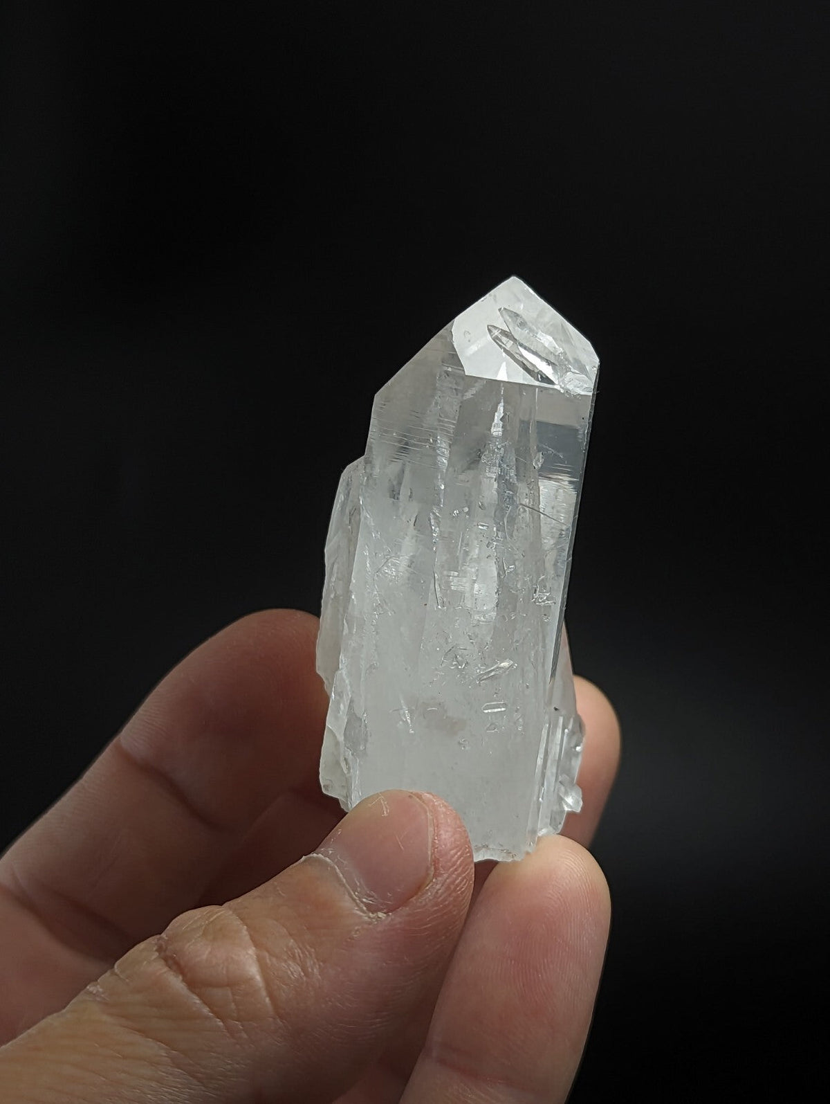 A clear, translucent quartz crystal with a pointed tip and visible internal striations.