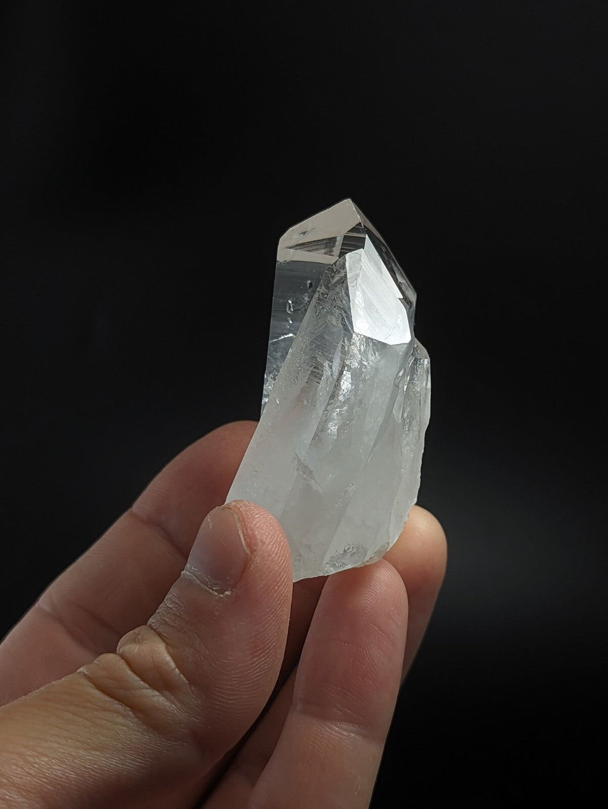 A translucent, clear quartz crystal with a pointed tip and natural facets.