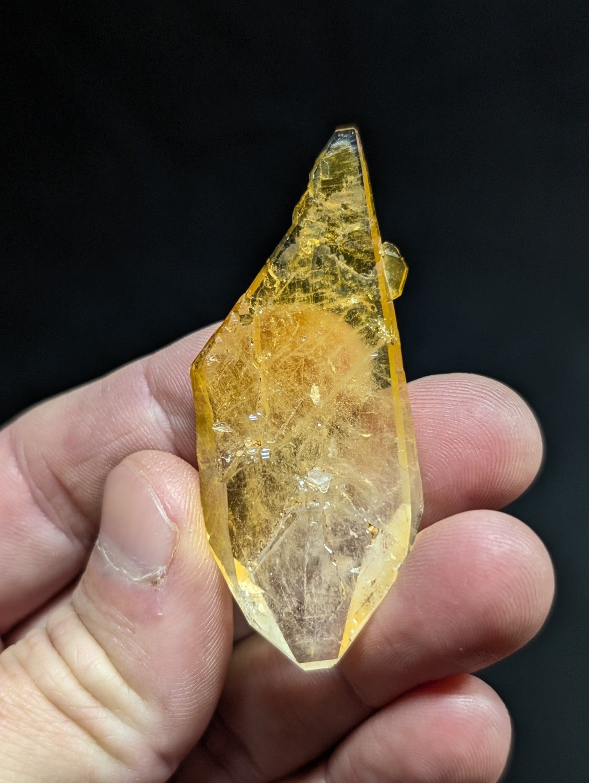 A translucent golden-yellow crystal with a faceted, pointed shape and visible internal inclusions.