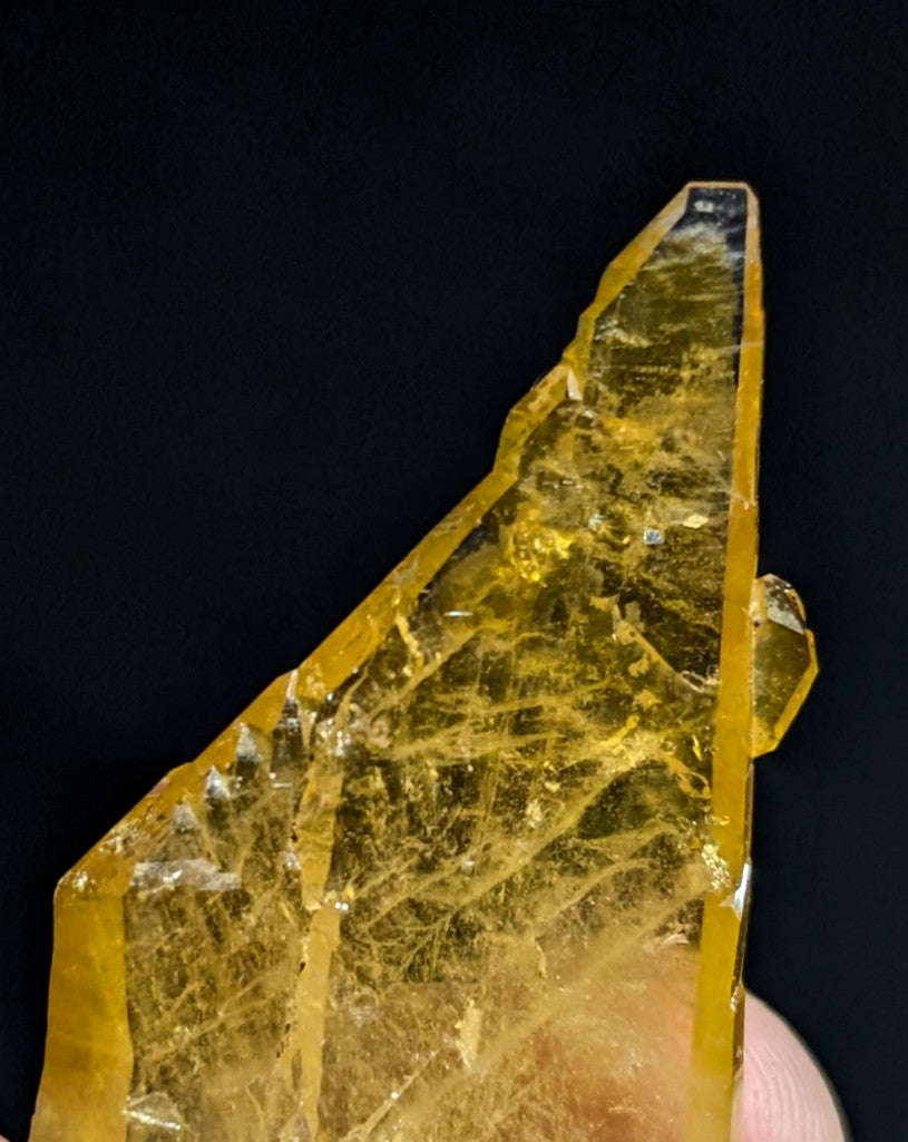 A translucent golden-yellow crystal with a faceted, angular shape and visible internal crystalline inclusions.