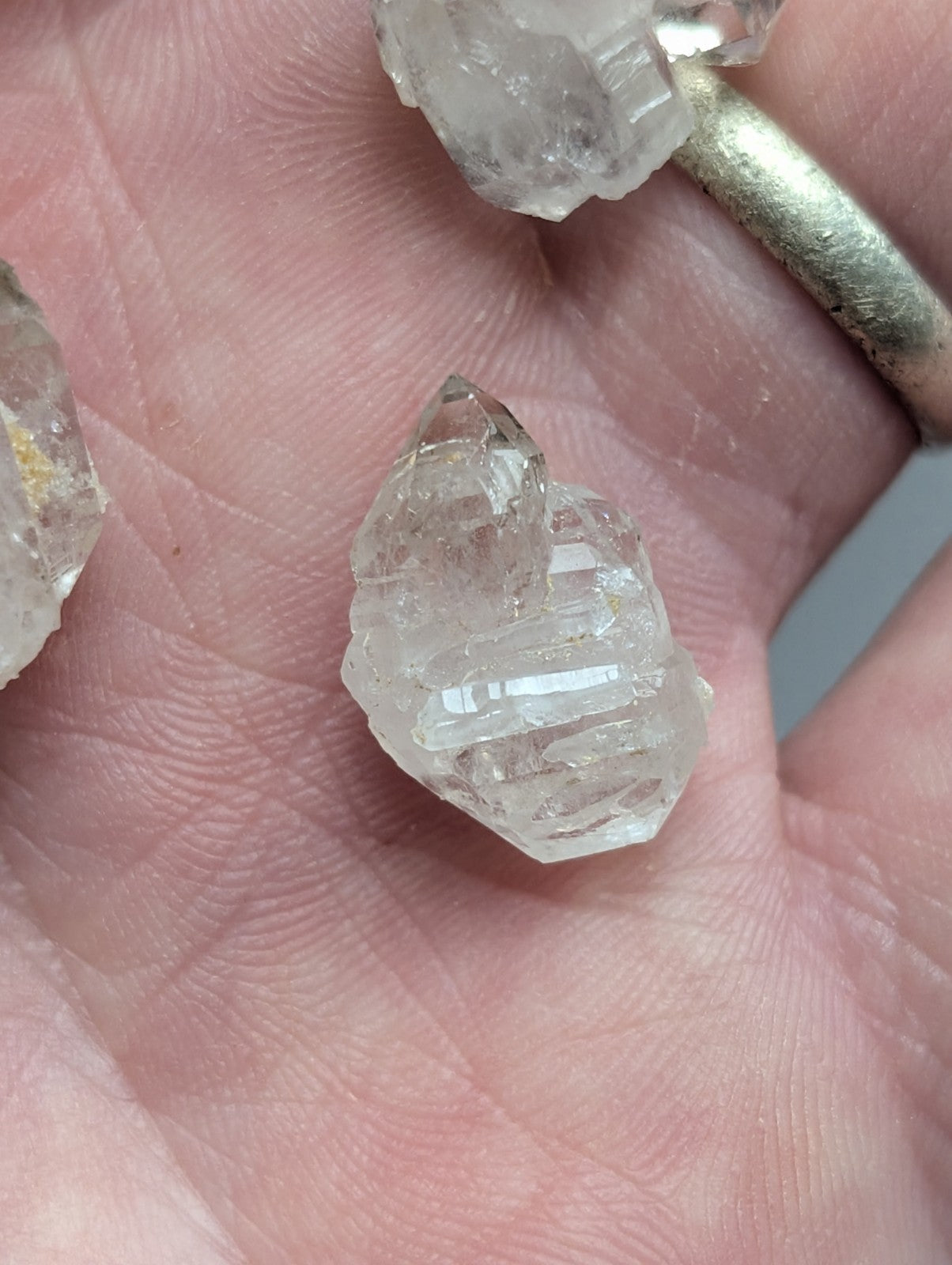 Clear quartz crystal cluster held in hand.