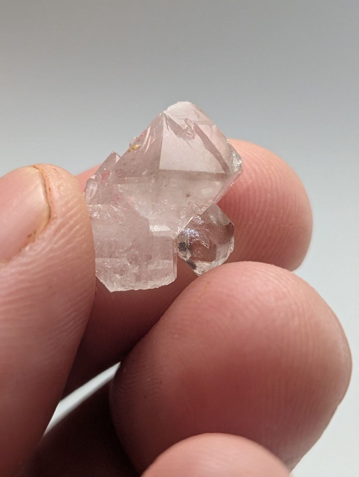 A translucent, pale pink quartz crystal cluster with sharp geometric facets and a natural, rough-edged formation.
