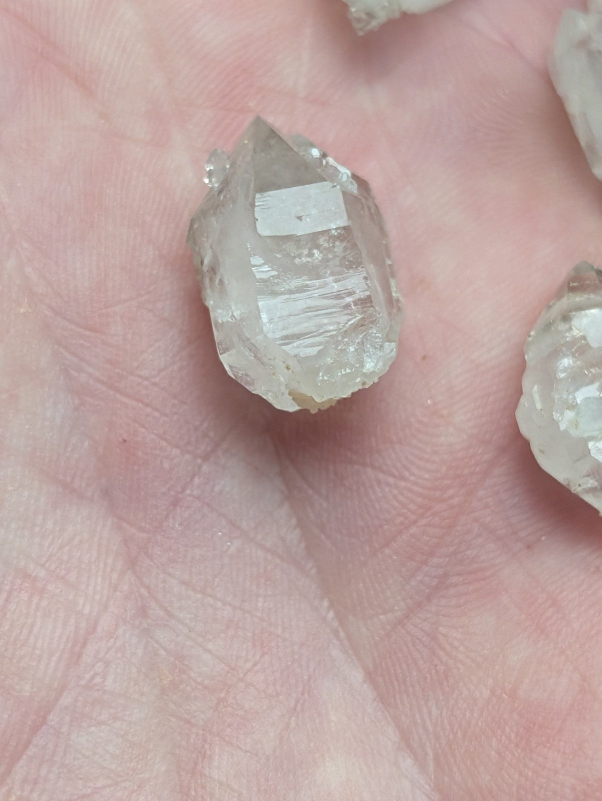 A translucent, clear quartz crystal with visible internal striations and a pointed tip.