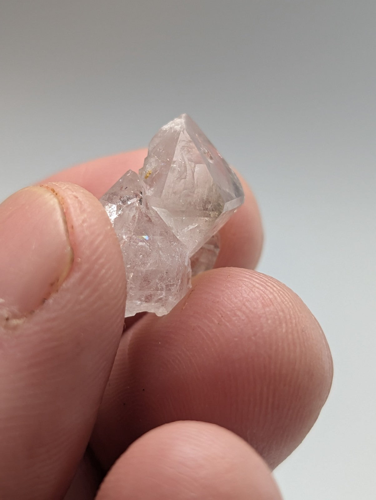 A translucent, clear quartz crystal cluster with sharp geometric facets and a slightly rough, natural surface.