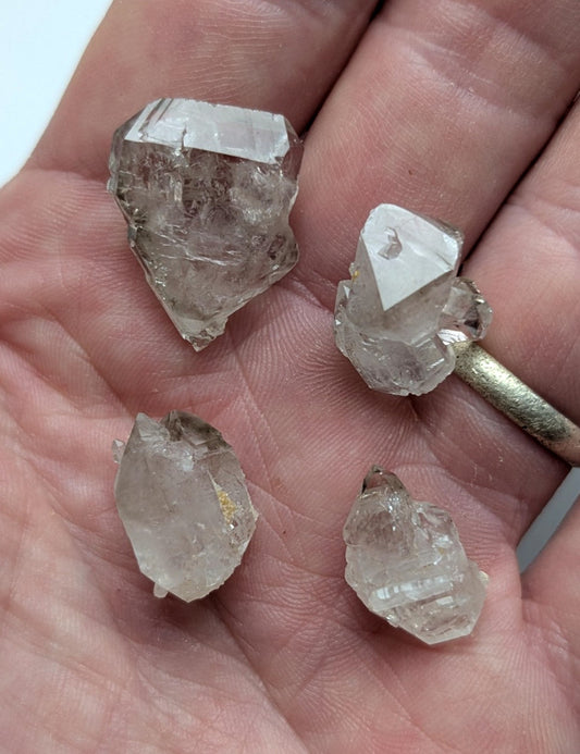 Four translucent, faceted quartz crystals with natural, irregular shapes and subtle internal inclusions.
