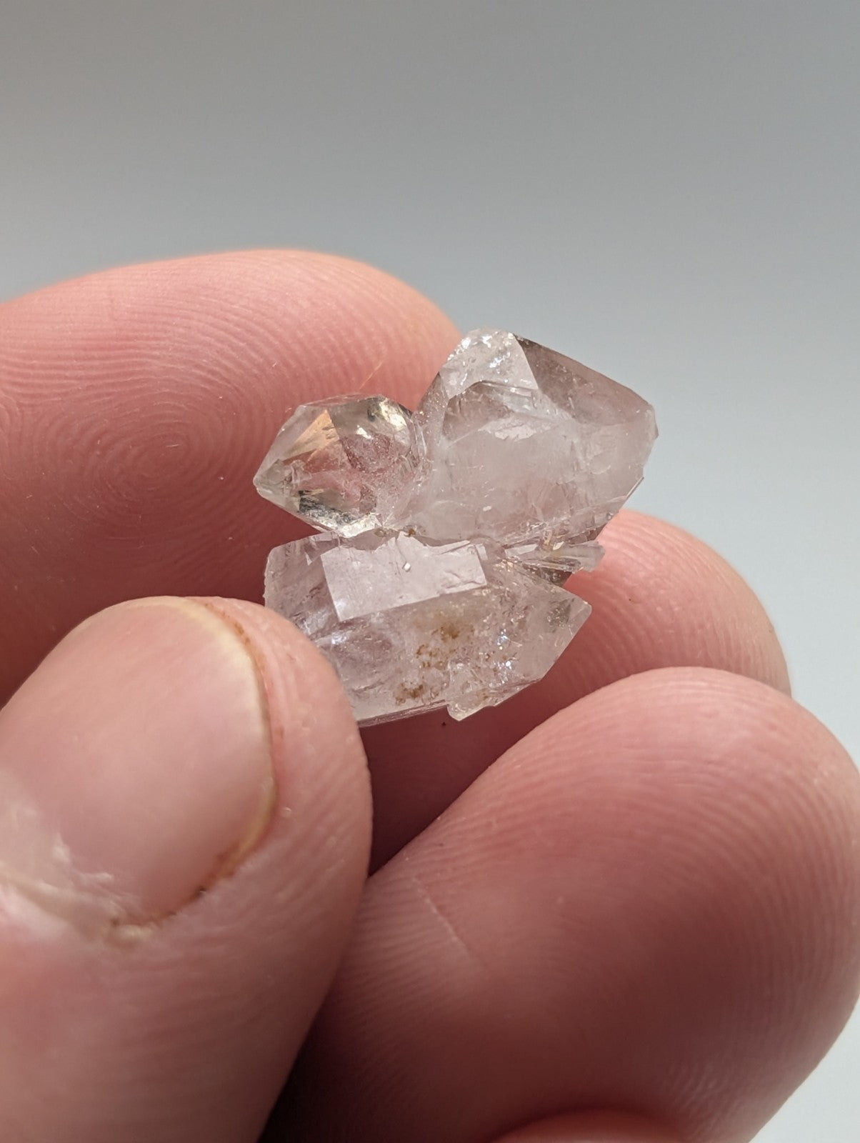 A cluster of clear, faceted quartz crystals held in a hand.