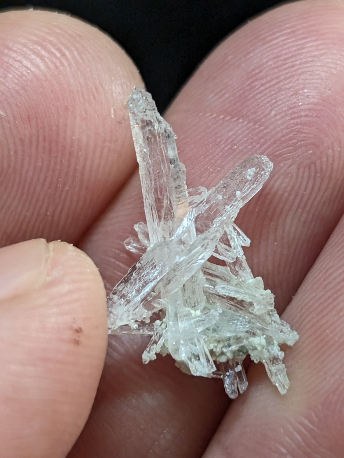 A clear, translucent crystal cluster with sharp, jagged edges and a slightly greenish tint at its base.