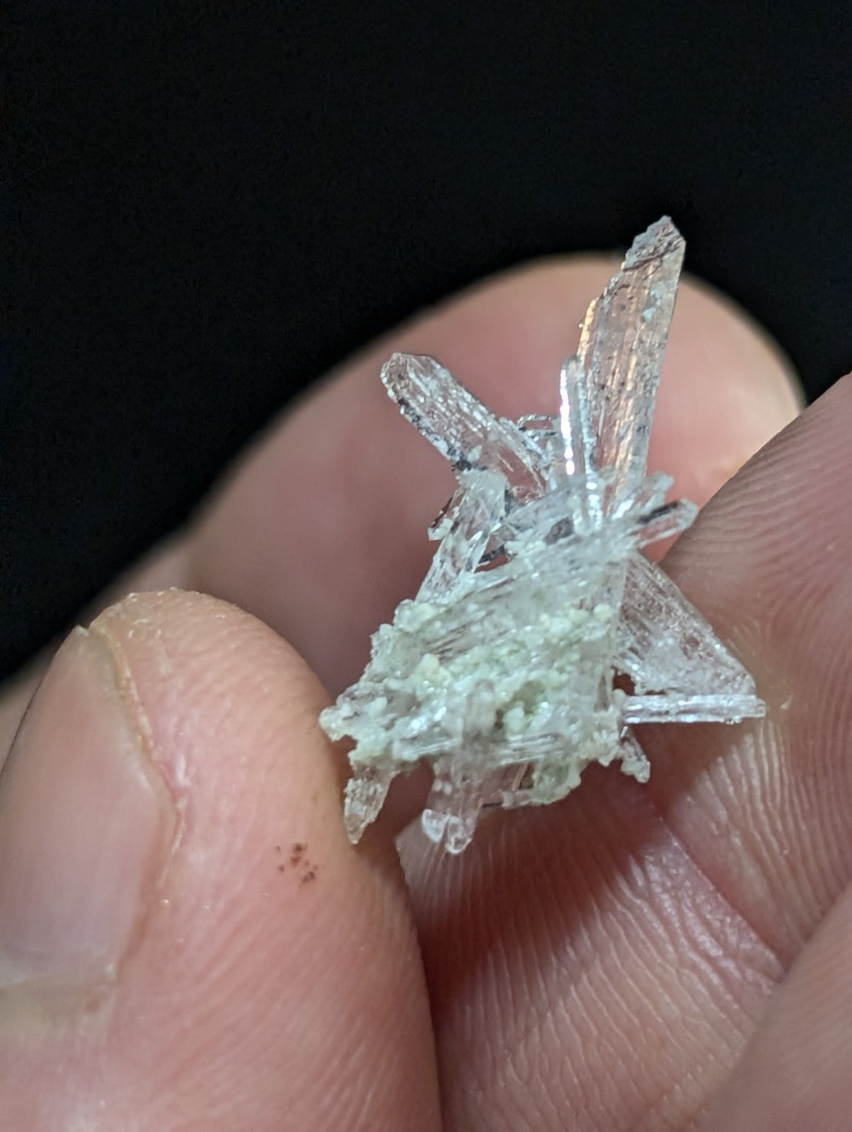 A translucent, crystalline mineral specimen with sharp, angular facets and a pale greenish tint at its base.