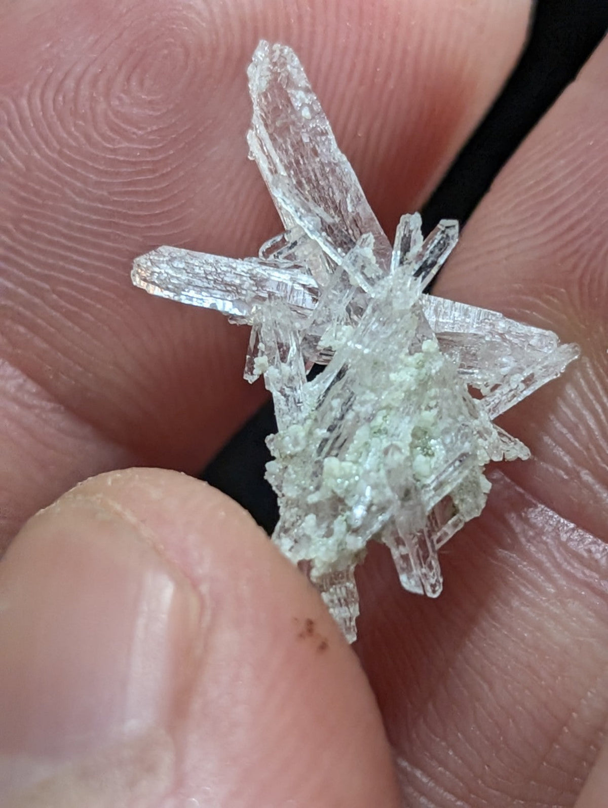 A translucent, star-shaped mineral specimen with sharp crystalline facets and a faint greenish tint.