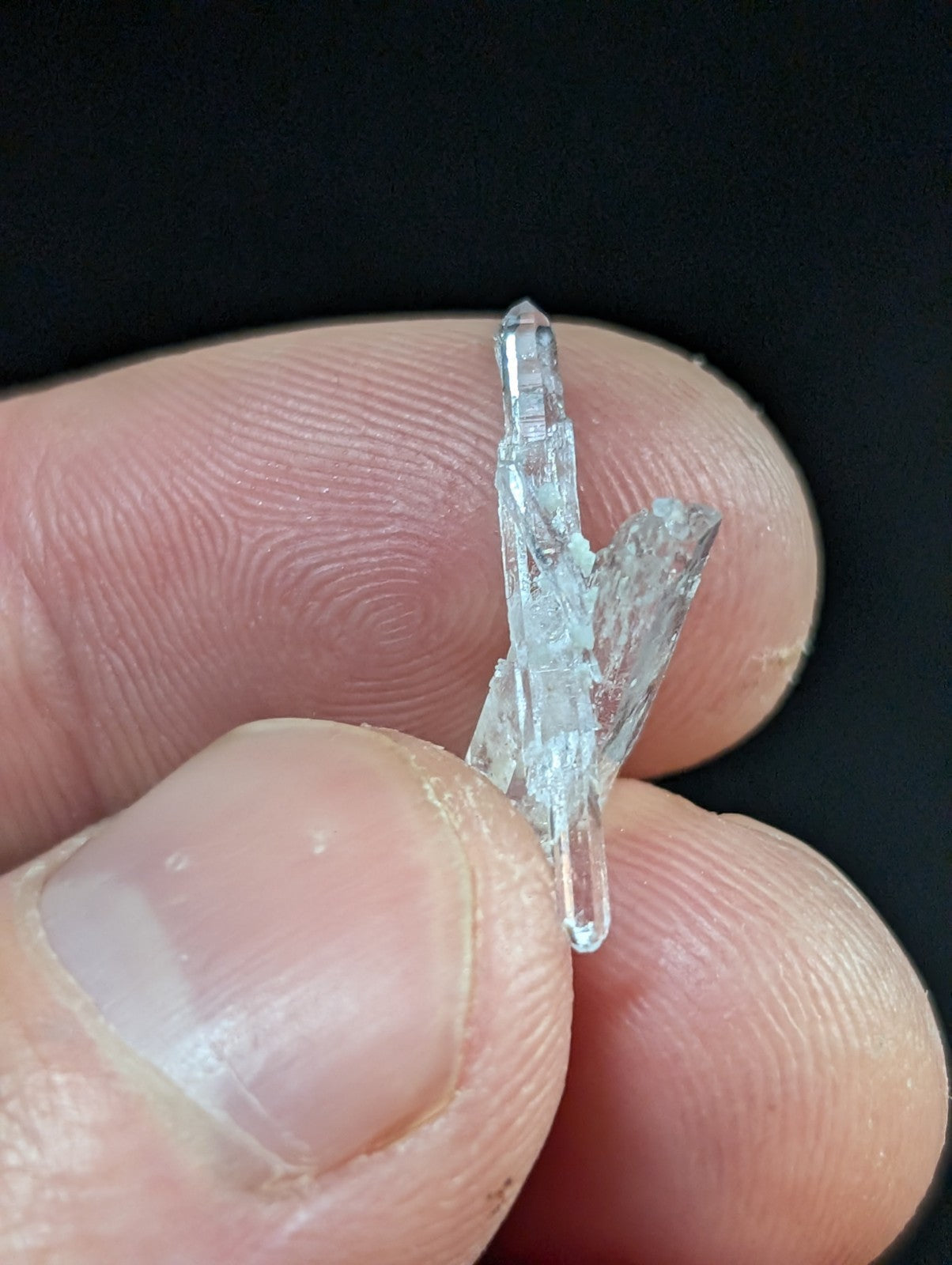 A clear, translucent quartz crystal with a pointed tip and jagged edges.