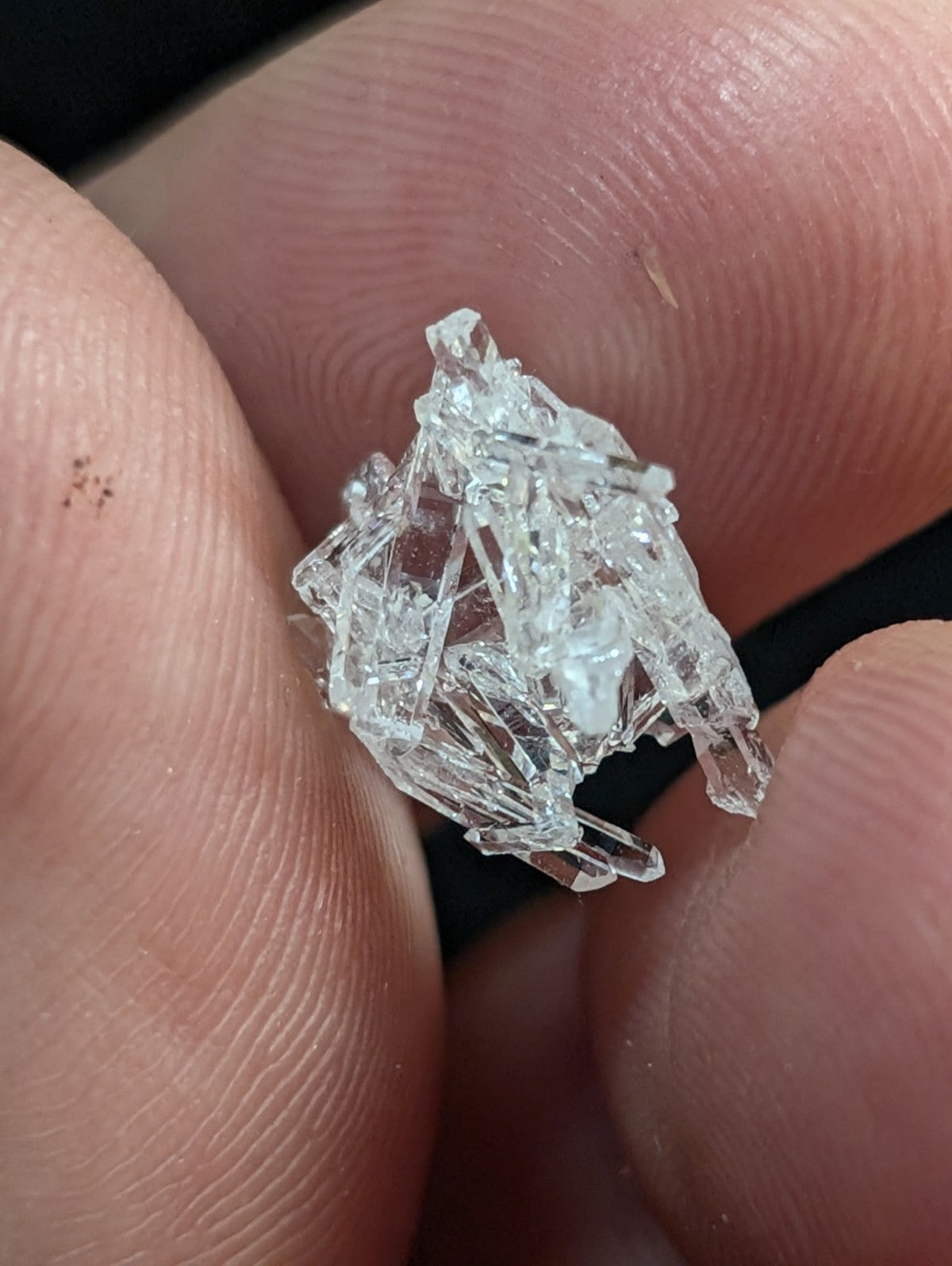 A clear, multifaceted crystal cluster with sharp edges and transparent facets.