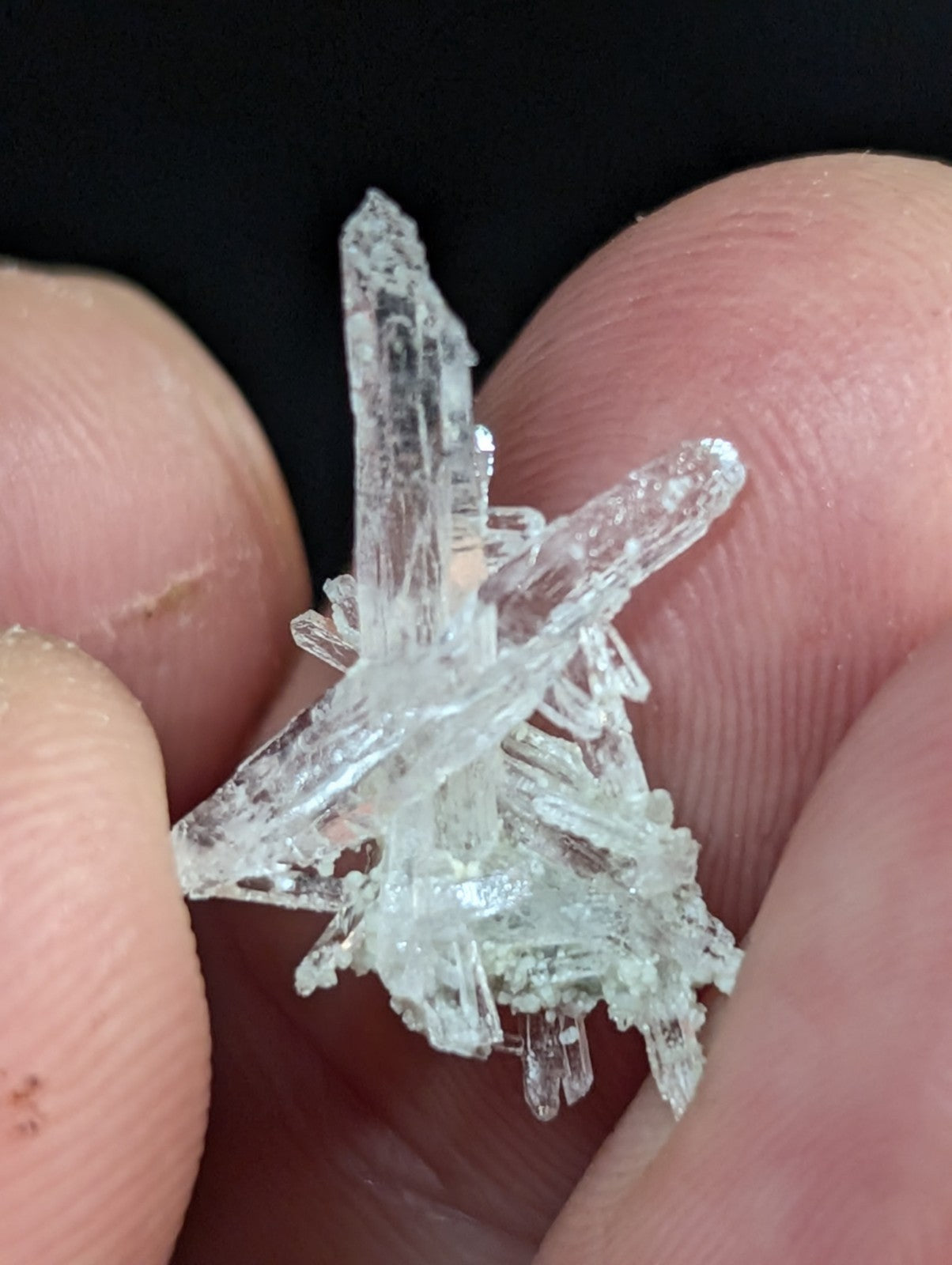 A clear, translucent crystal cluster with sharp, interlocking facets and a delicate, branching structure.