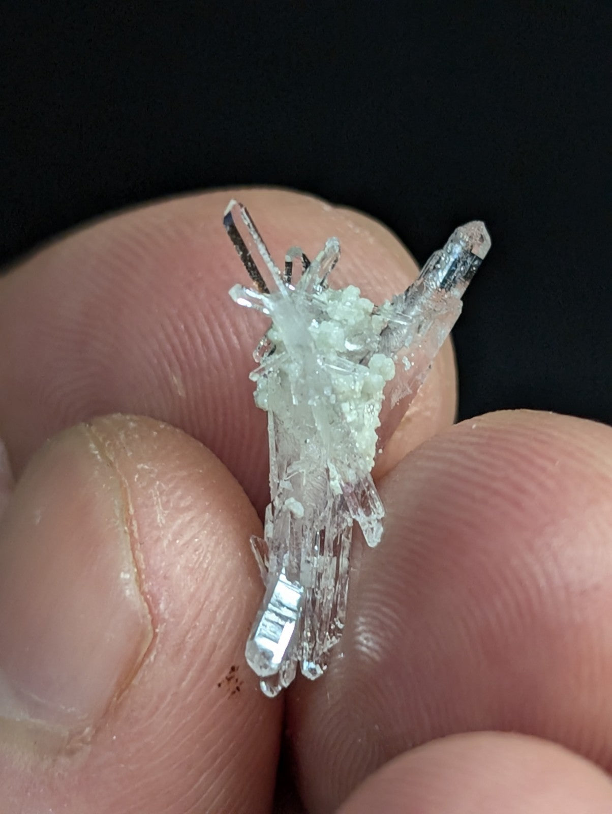 A translucent, clear quartz crystal cluster with sharp, angular points and a central mass of smaller crystalline formations.