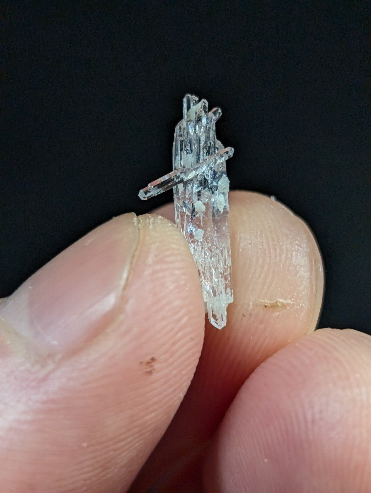A translucent, crystalline mineral specimen with a jagged, multi-faceted structure and faint blueish tint.