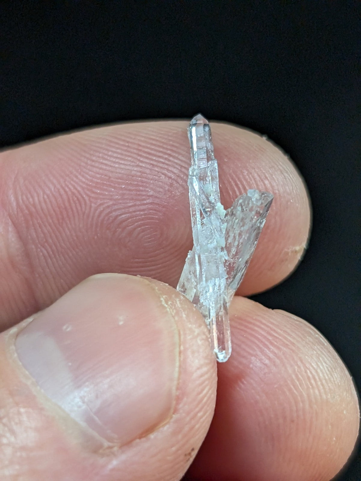 A clear, translucent quartz crystal with a pointed tip and jagged edges.
