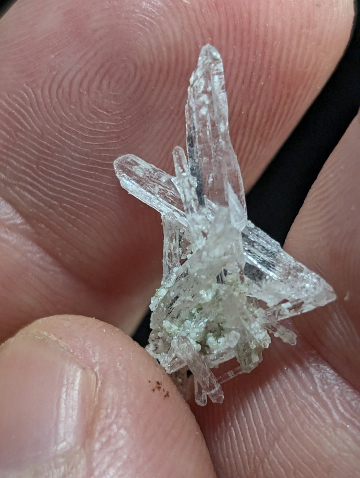 A clear, translucent crystal cluster with sharp, pointed facets and a slightly greenish tint at its base.