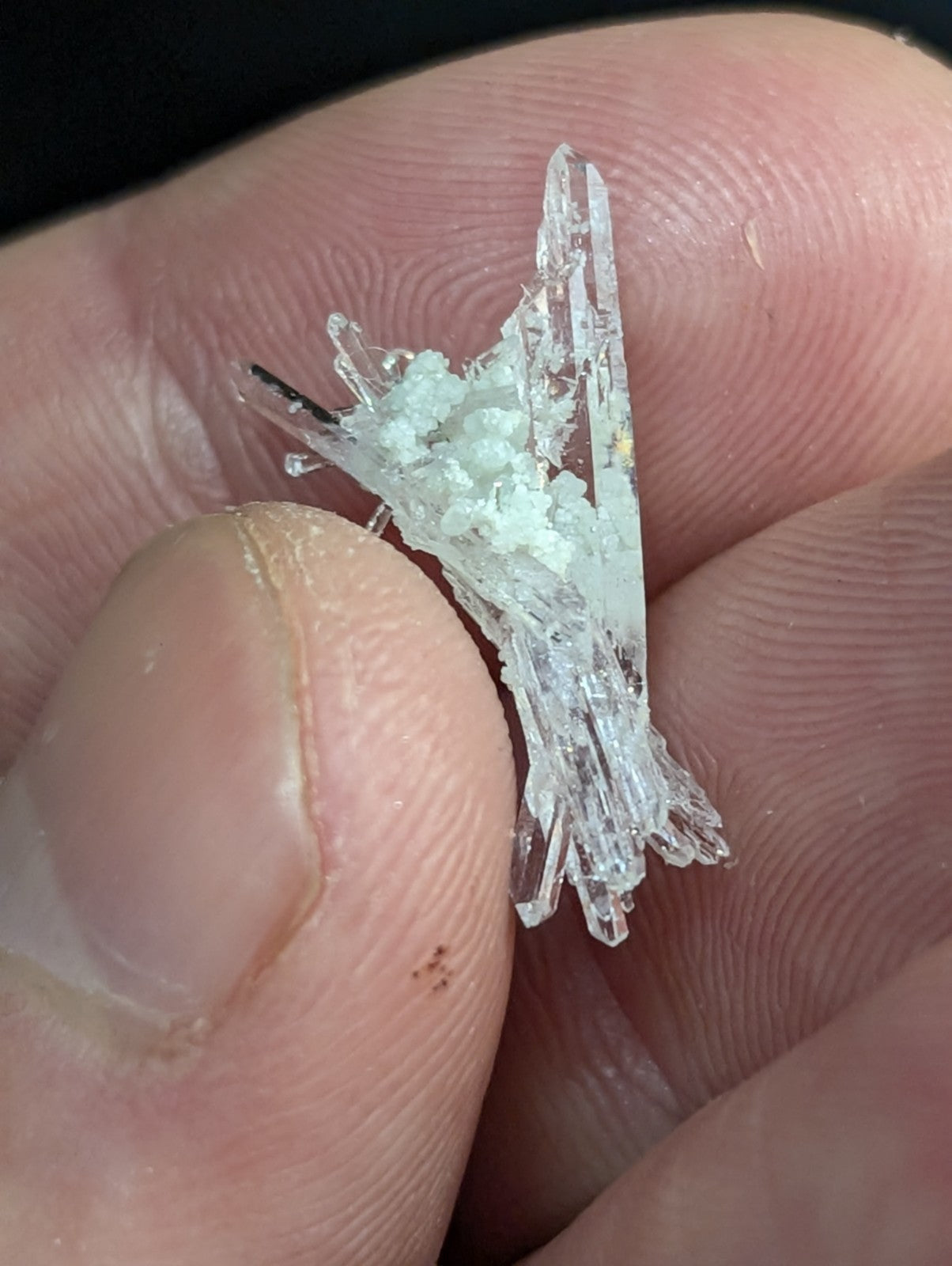 A delicate, translucent crystal cluster with sharp, jagged edges and a faint milky white hue.