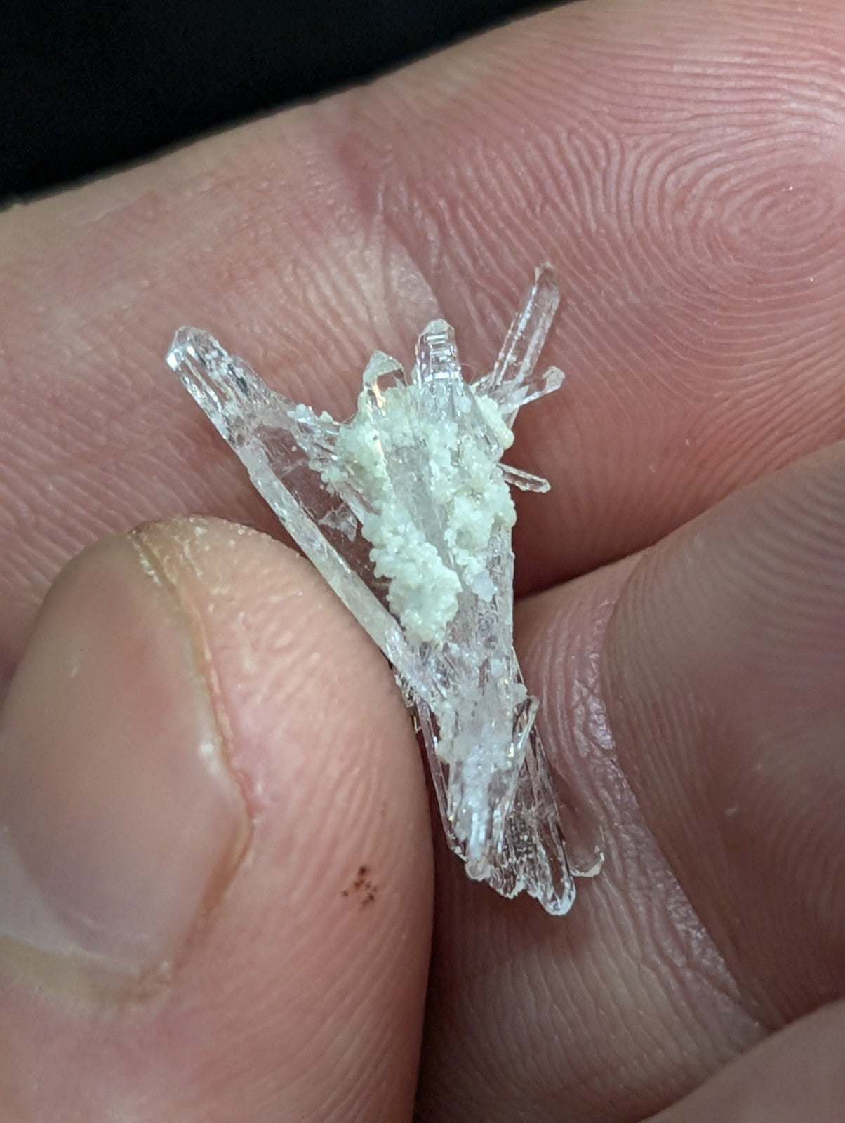 A translucent, crystalline mineral specimen with sharp, angular facets and a pale greenish-white core.