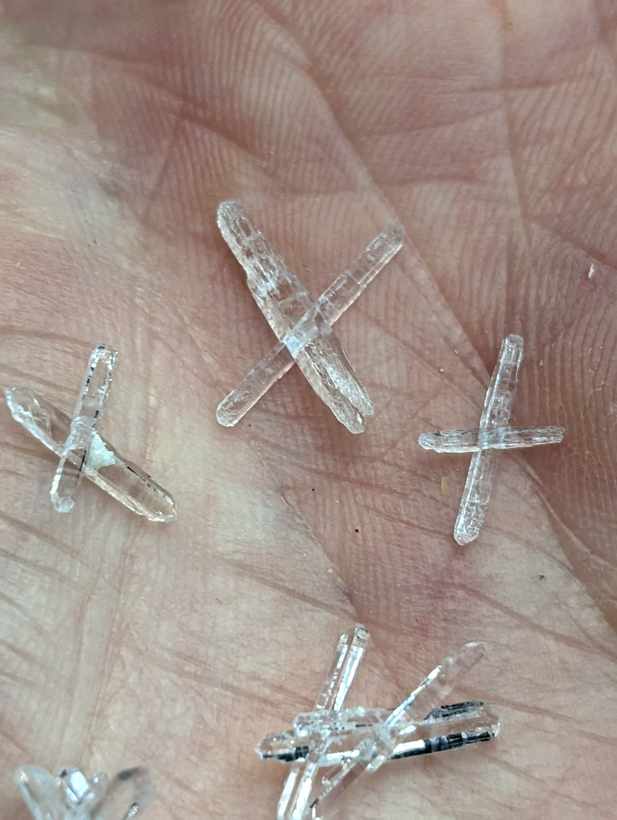 Clear translucent quartz crystal cross-shaped pieces resting in palm from a+ solution set of 8 jeffrey quarry arkansas