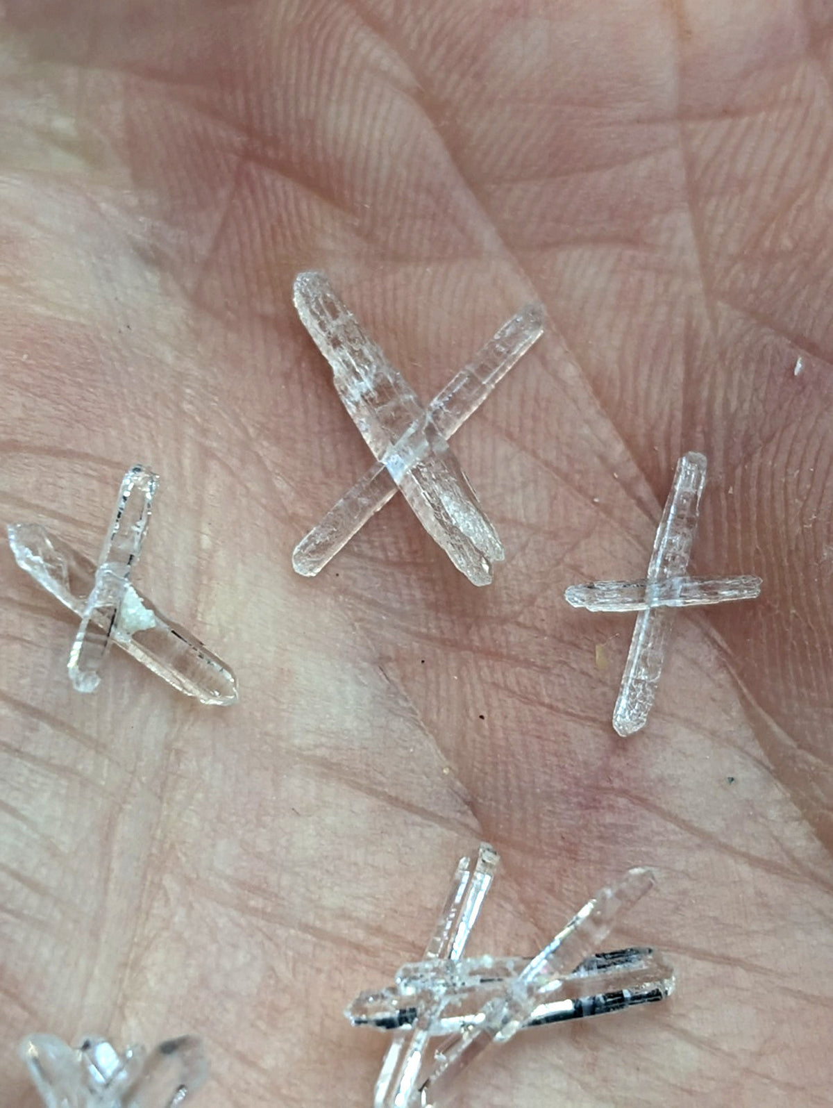 Clear translucent quartz crystal cross-shaped pieces resting in palm from a+ solution set of 8 jeffrey quarry arkansas