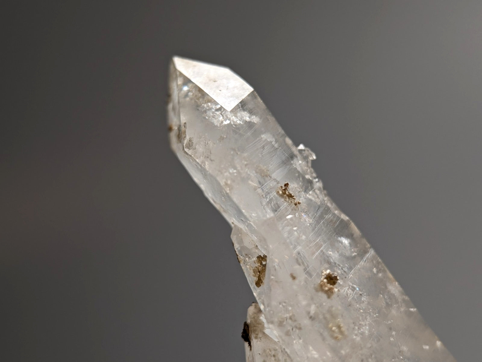 A clear quartz crystal with pointed tip and natural inclusions featuring uv reactive cookeite from jeffrey quarry arkansas
