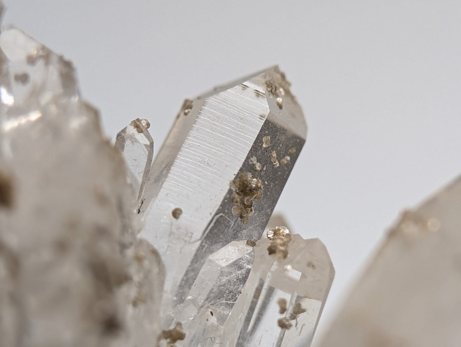 A clear quartz crystal with faceted transparent surface and subtle golden inclusions from Jeffrey Quarry Arkansas