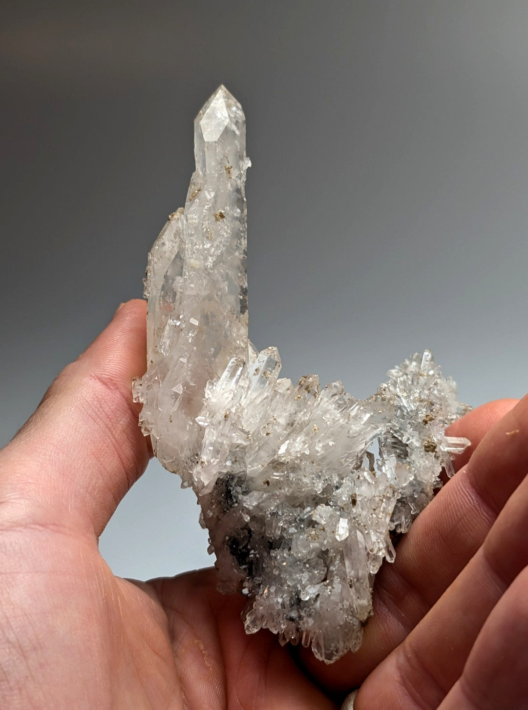 A translucent quartz crystal cluster with a sharp central spike and uv reactive cookeite from Jeffrey Quarry Arkansas