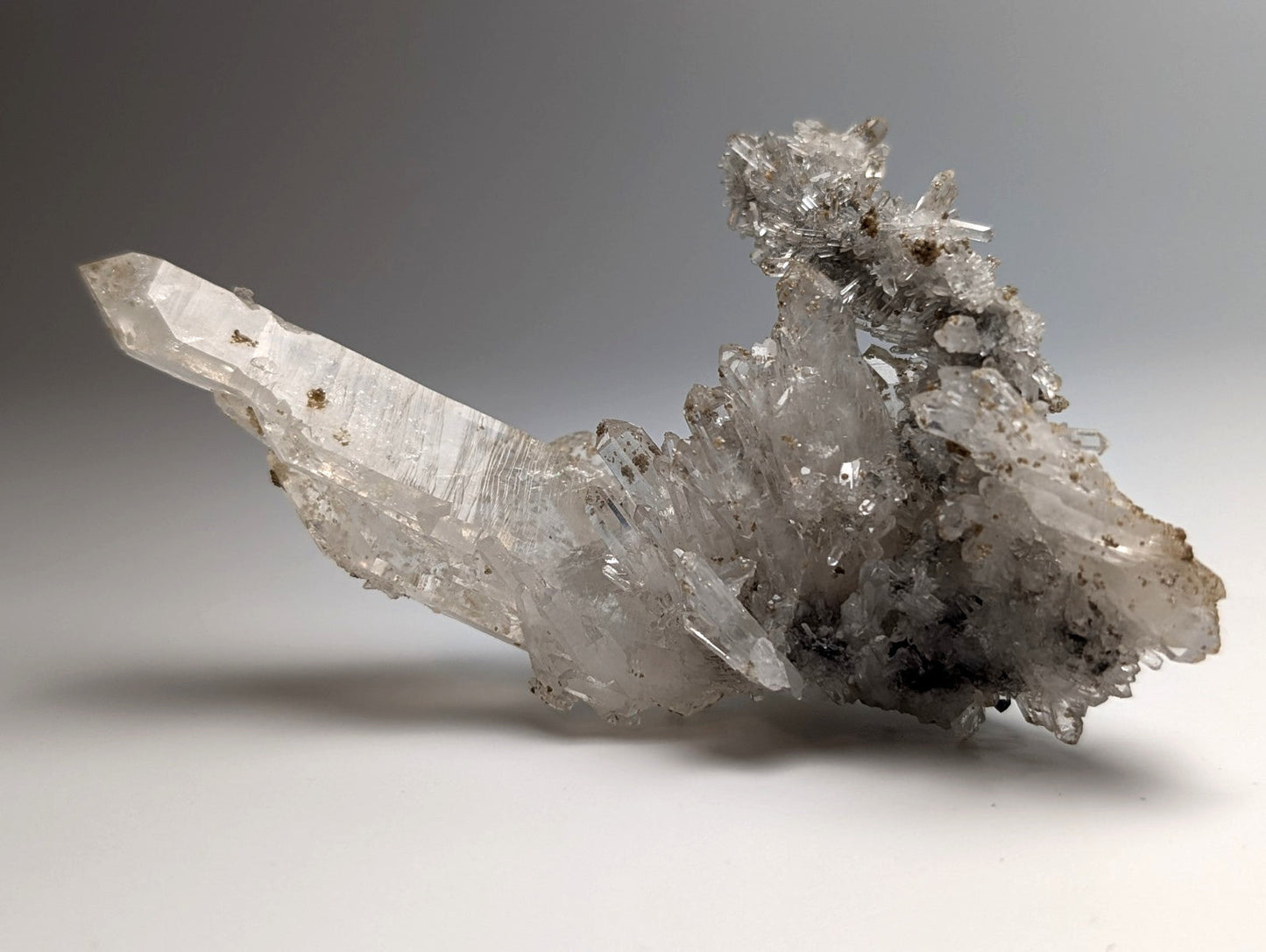 A translucent quartz crystal cluster with a sharp prismatic spike and uv reactive cookeite from jeffrey quarry arkansas