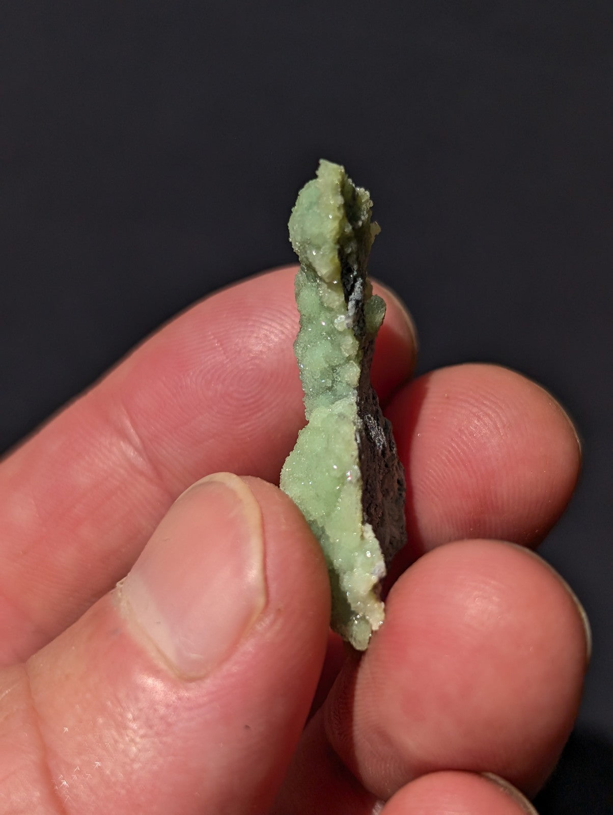 A pale green, crystalline mineral specimen with a rough, jagged surface and subtle translucency.