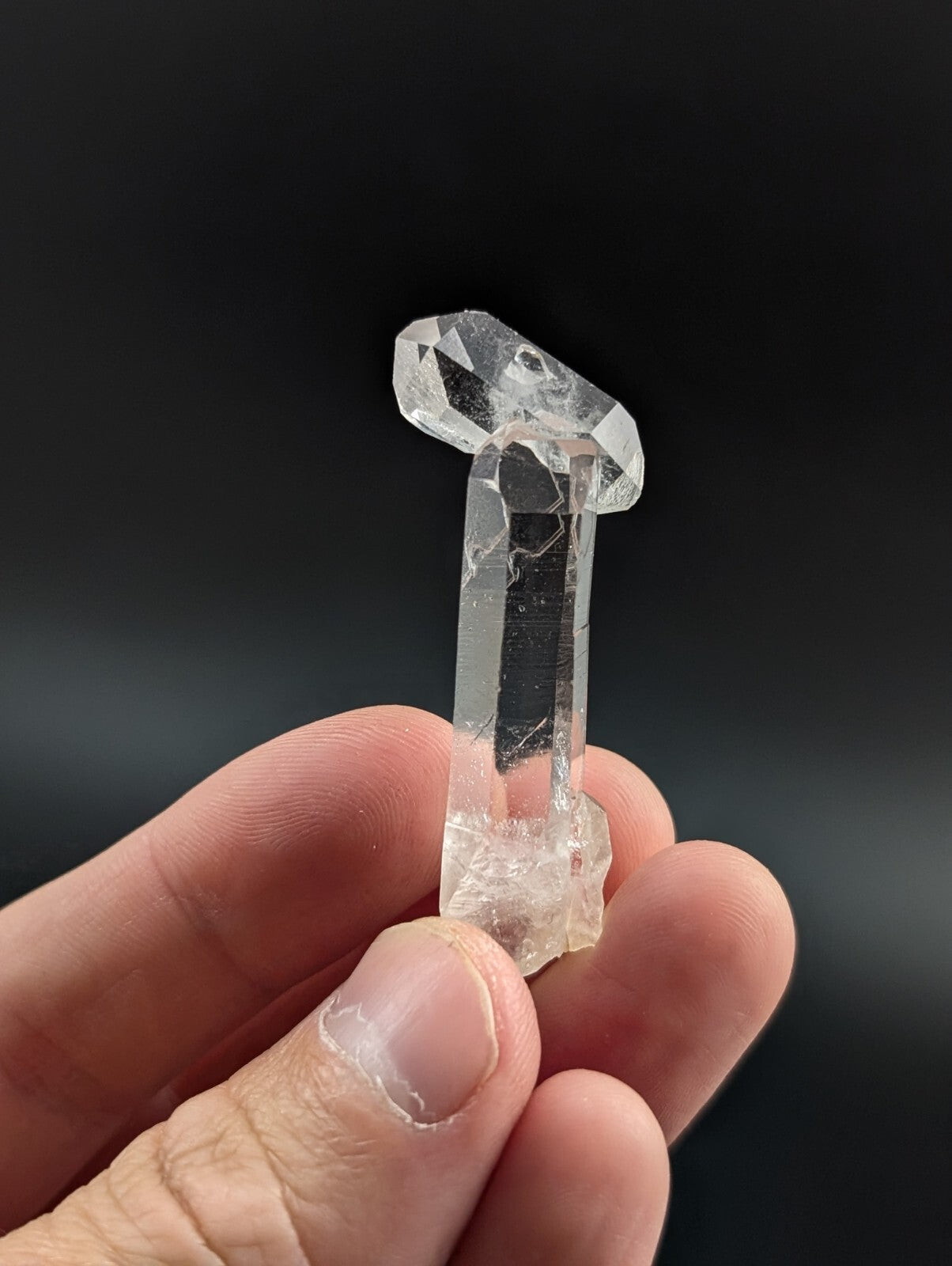 A clear, faceted quartz crystal with a distinct pointed top and rough base.