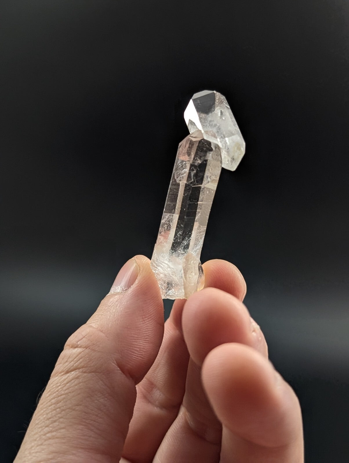 A clear, translucent quartz crystal with a faceted top and natural internal inclusions.