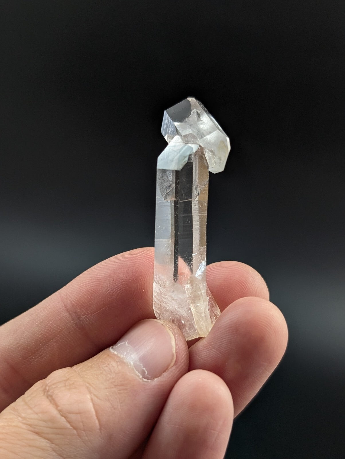 A clear, translucent quartz crystal with a pointed top and natural facets.