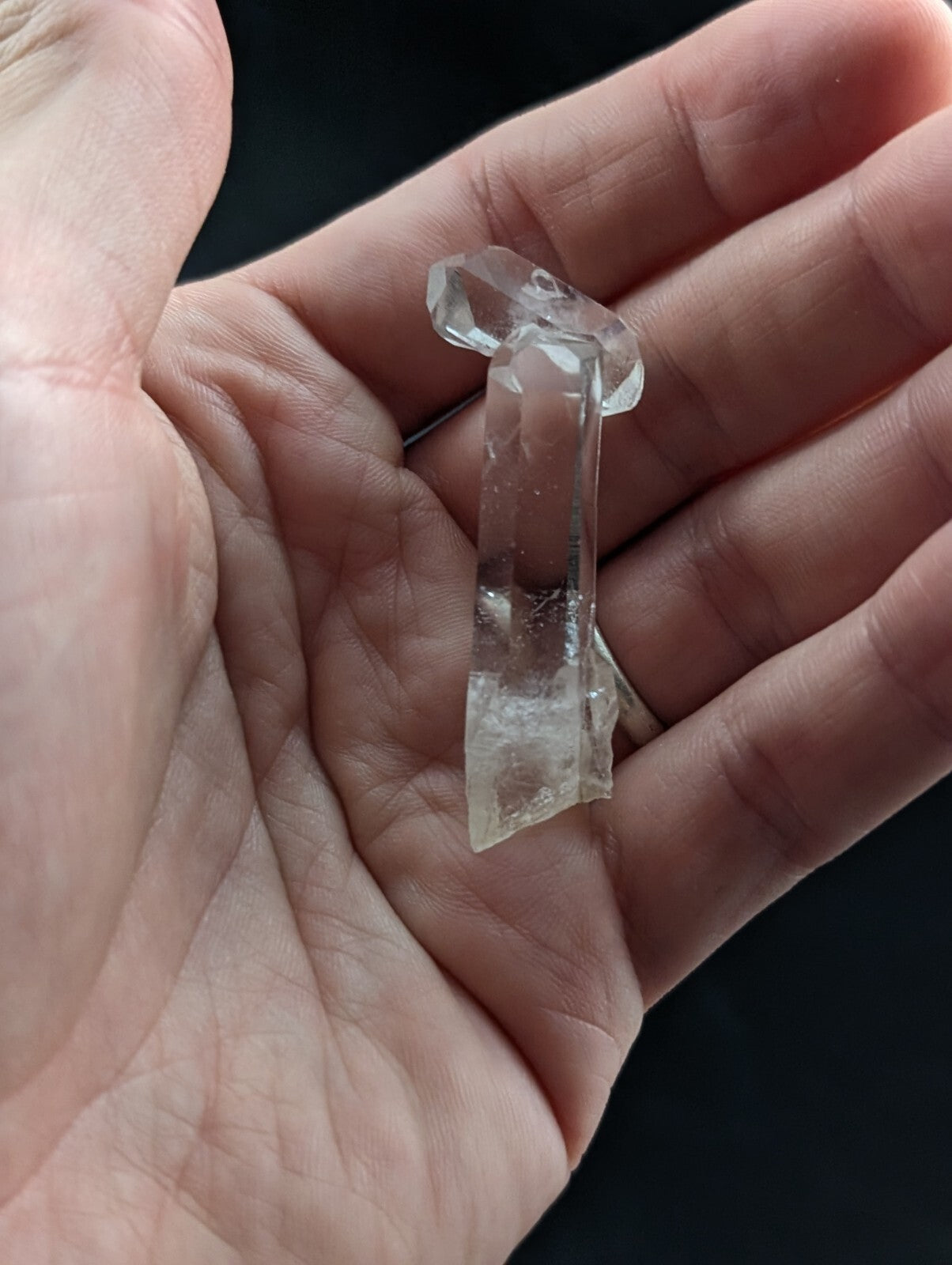 A clear, translucent quartz crystal with a natural, faceted top and rougher base.